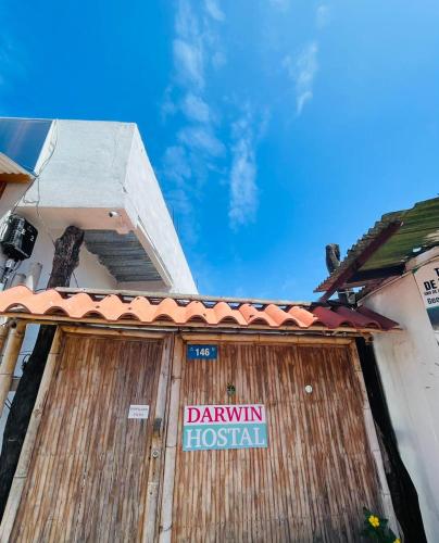 Una gran puerta de madera con un cartel. en Hostal Darwin B&B, en Puerto Ayora