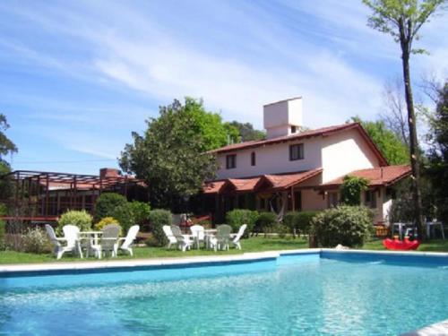 a swimming pool with chairs and a house at Aldea Kleinwald in Villa General Belgrano