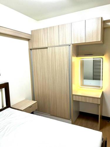 Schlafzimmer mit einem Bett und einem Schrank mit einem TV in der Unterkunft Al Caja Resort Condotel in Manila