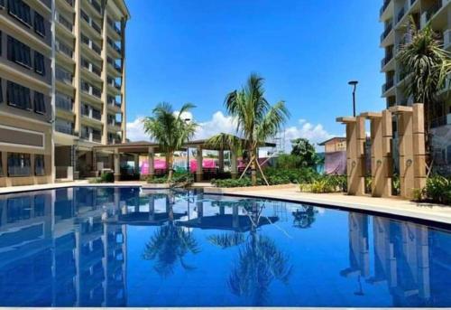 ein Pool mit Palmen und ein Gebäude in der Unterkunft Al Caja Resort Condotel in Manila