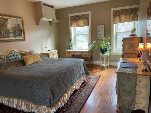 a bedroom with a bed and a table and windows at The Hollinger House in Lancaster