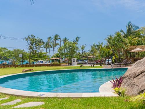 a swimming pool in a park with palm trees at Hotel Velas do Engenho in Ilhabela