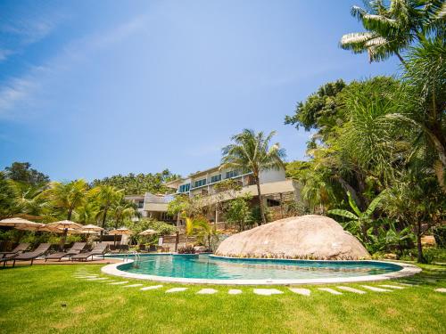 a pool at a resort with chairs and a building at Hotel Velas do Engenho in Ilhabela