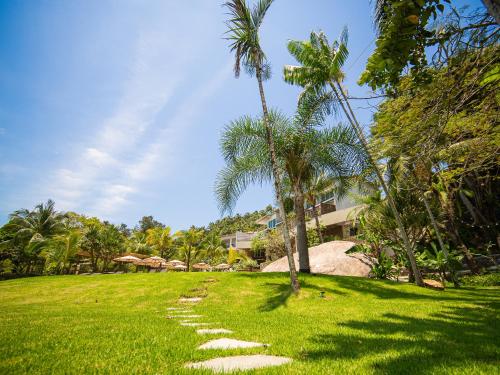 a path in the grass with palm trees and buildings at Hotel Velas do Engenho in Ilhabela