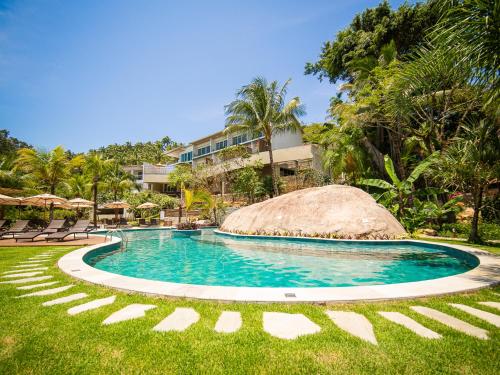 a swimming pool in a resort with chairs and trees at Velas do Engenho in Ilhabela