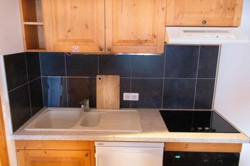 una cucina con lavandino e una parete di piastrelle nere di Rez de chalet, Sauna extérieur, Wifi, 4-6 pers, 50m2 a Isola 2000