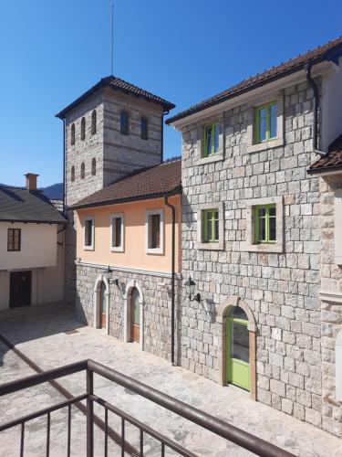 a group of buildings with a clock tower in the background at Turistički centar Andrićgrad in Višegrad
