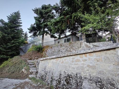eine Steinmauer mit Bäumen darüber in der Unterkunft Greponis House in Ano Trikala