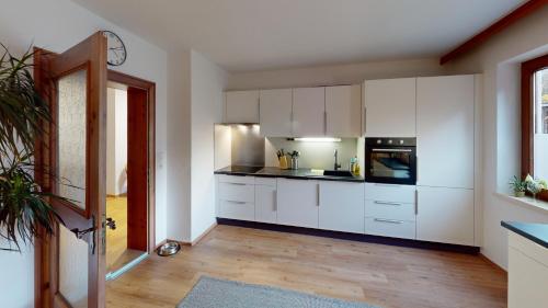 a kitchen with white cabinets and a black appliance at Haus Alberto - Haus mit 2 Ferienwohnungen in Ötztal-Bahnhof