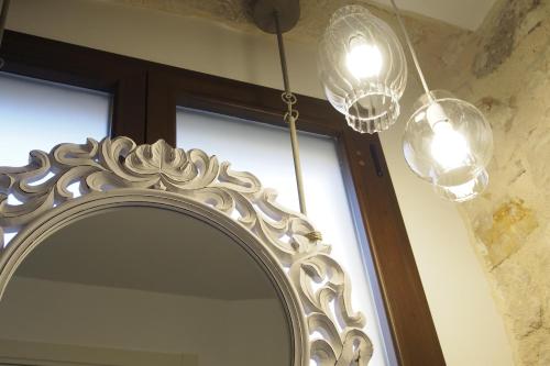 a mirror with two lights and a window at Terrazzani Suite in Comiso
