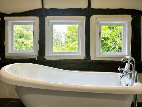 a bath tub in a bathroom with two windows at The Manor at Abberley in Abberley