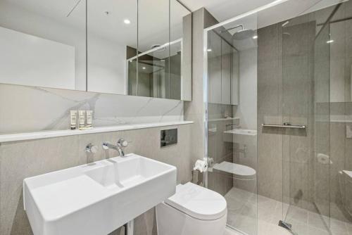 a white bathroom with a sink and a toilet at New Stature Southbank Luxury in Melbourne