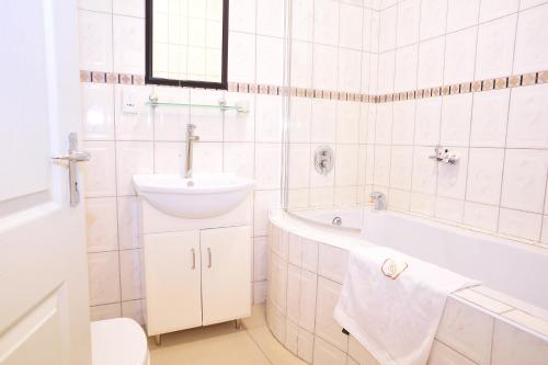a white bathroom with a sink and a bath tub at Hotel Destiny in Ongwediva