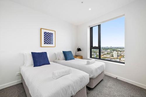2 bedden in een witte kamer met een raam bij Stunning Stature Southbank 2bed in Melbourne