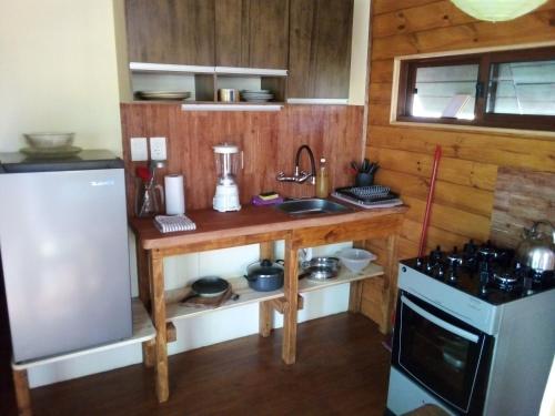 a kitchen with a wooden counter with a sink and a refrigerator at Sietevestidos Casa Ecológica - Punta Negra in Punta Colorada