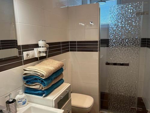 a bathroom with a shower and a pile of towels at ApartmánTonki v centre mesta Piešťany in Piešťany