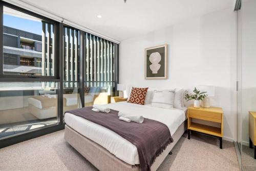 a bedroom with a large bed and a balcony at Riverview Parkhouse Abbotsford in Melbourne
