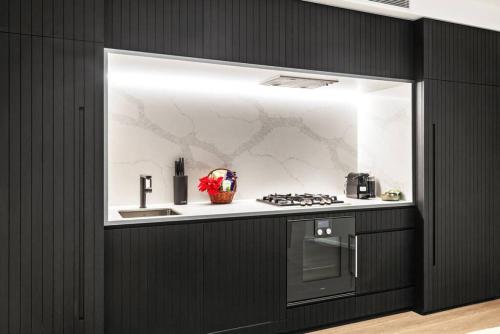 a kitchen with a counter with a stove and a sink at Riverview Parkhouse Abbotsford in Melbourne