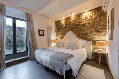 1 dormitorio con 1 cama grande y pared de piedra en Medieval Cottage, en Monte San Savino