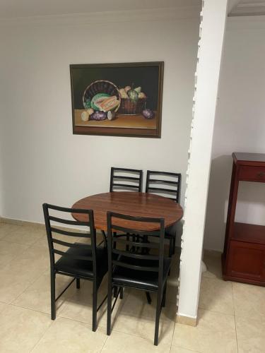 uma mesa de madeira com duas cadeiras e uma pintura na parede em Alojamientos Cartagena Edificio Los Delfines em Cartagena das Índias