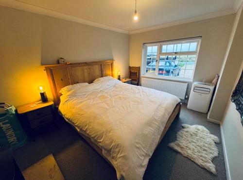 ein Schlafzimmer mit einem großen Bett und einem Fenster in der Unterkunft West Wittering Family Home in West Wittering