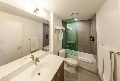 Baño blanco con lavabo y aseo en The Laundry Rooms Station Park Kitchener, en Kitchener
