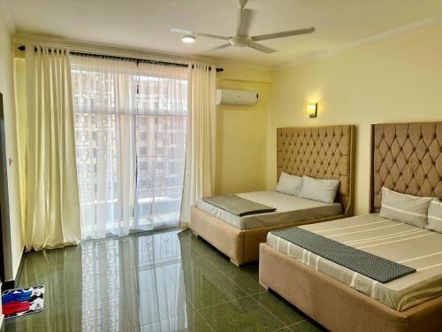 ein Hotelzimmer mit 2 Betten und einem Fenster in der Unterkunft Oceans-Opulence/3BR-5 BEDS in Daressalam