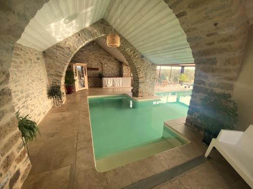 uma piscina interior numa casa com um arco em Les Caselles, Gîte et Maison d'hôtes em Saint-Beauzély