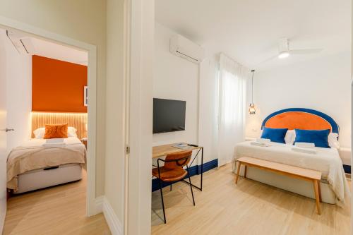 a bedroom with two beds and a desk and a television at Indulge en Sevilla Faustino 45 in Seville