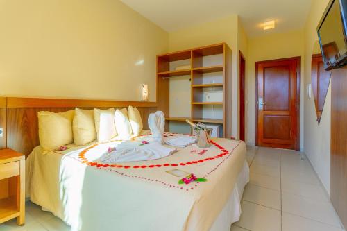 a bedroom with a large white bed with decorations on it at Rede Andrade Terra Brasil in Porto Seguro