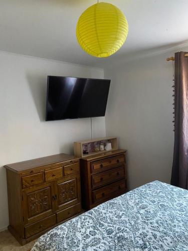a bedroom with a bed and a dresser and a television at Refugio Renacer in Pisco Elqui