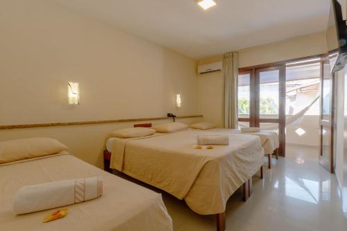 a hotel room with three beds and a window at Rede Andrade Terra Brasil in Porto Seguro