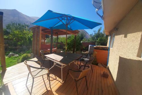 a table and chairs with a blue umbrella on a deck at Refugio Renacer in Pisco Elqui