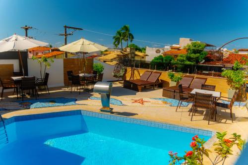 a swimming pool with chairs and tables and umbrellas at Rede Andrade Terra Brasil in Porto Seguro