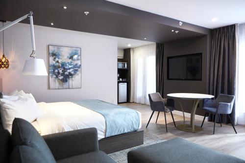 a bedroom with a bed and a table and chairs at Hôtel Cofortel in Quebec City