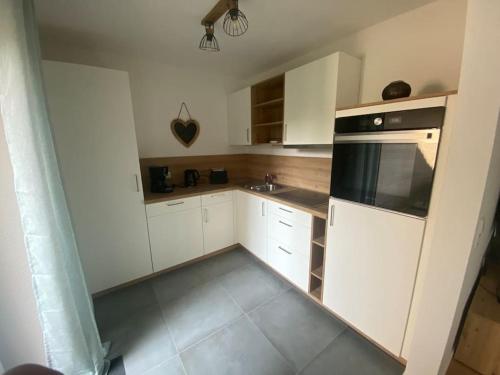 a kitchen with white cabinets and a black appliance at Deichperle, ihr Ankerplatz! in Büsumer Deichhausen