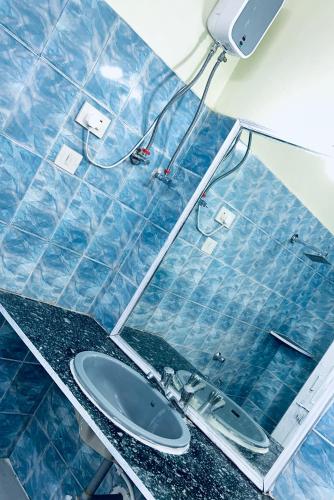 a blue tiled bathroom with a sink and a mirror at Chandrajyoti Villa 2 Garden Facing. in Nagpur