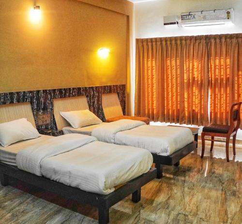 a room with three beds and a table and a chair at Hotel Prasanth in Ernakulam