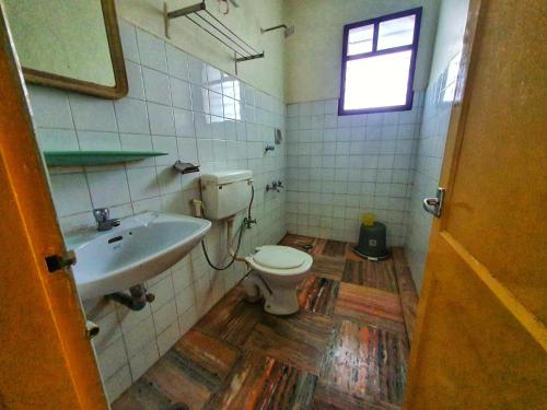 a bathroom with a toilet and a sink and a window at Hotel Prasanth in Ernakulam