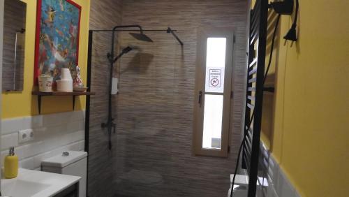 a bathroom with a shower with a toilet and a window at Villa Saudade, casa entre encinas in El Castillo de las Guardas