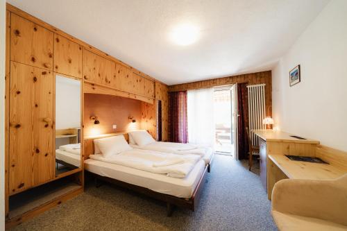 een slaapkamer met 2 bedden in een kamer met houten wanden bij Hotel Old JNN in Klosters Serneus