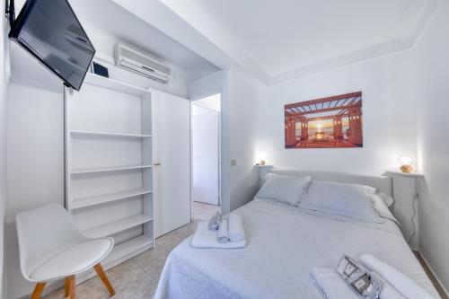 a white bedroom with a bed and a chair at FAMILY APARTMENT SEA VIEW in Nice