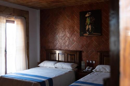 a bedroom with two beds and a painting on the wall at Hotel Casa Mixteca in Huajuapan de León