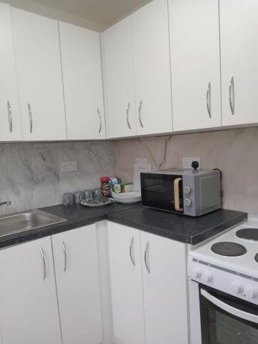 a kitchen with white cabinets and a microwave at Good priced double bed rooms in harrow with shared bathrooms in Hatch End
