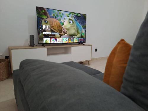 una sala de estar con TV con dos ranas en la pantalla en The Home E&N, en Gáldar