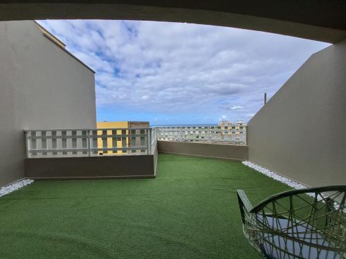 een balkon met groene vloeren en een stoel erop bij The Home E&N in Gáldar