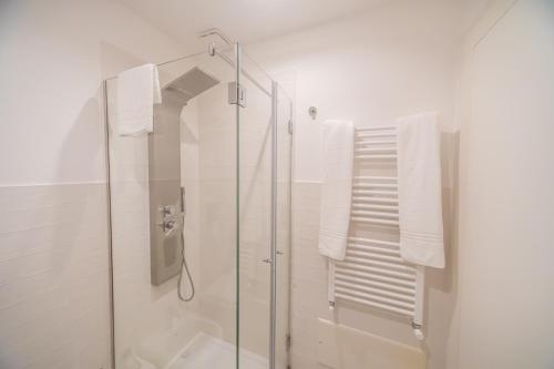 La salle de bains blanche est pourvue d'une douche et de serviettes blanches. dans l'établissement HAPPYROOMS, à Bacoli