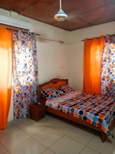 een slaapkamer met een bed met oranje gordijnen erin bij YILIMDE APPARTEMENTS in Ouagadougou