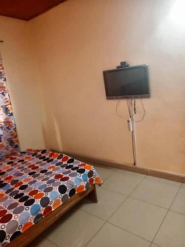 een slaapkamer met een bed en een tv aan de muur bij YILIMDE APPARTEMENTS in Ouagadougou