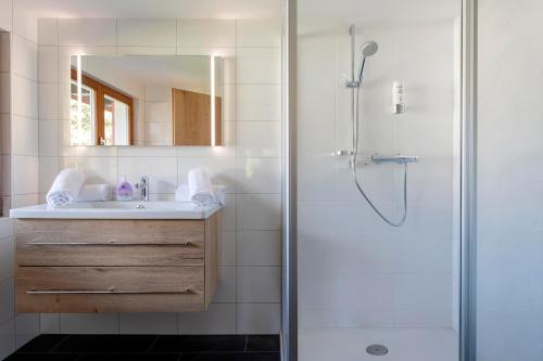 Un baño con ducha, lavabo y espejo. en Drei Türme Top A2, en Schruns